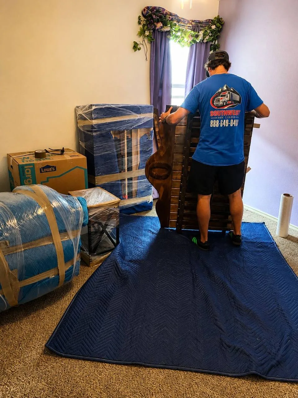 Southwest Van Lines mover preparing furniture with protective blankets and wrap